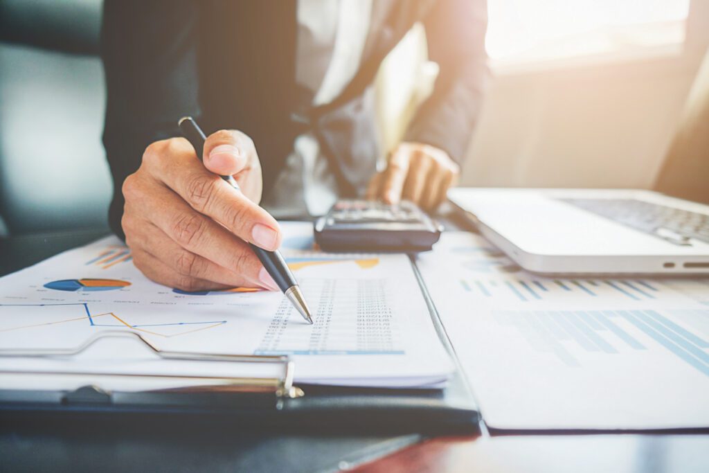 planejamento e gestão financeira: alicerces para o sucesso no escritório de arquitetura 1 mão de empresário com caneta analisando dados em relatório financeiro, representando a importância do planejamento para manter a saúde financeira de um escritório de arquitetura.