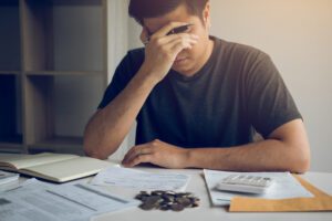os principais erros financeiros que pequenas empresas cometem 5 homem com expressão estressada fazendo contas e identificando erros financeiros em documentos.
