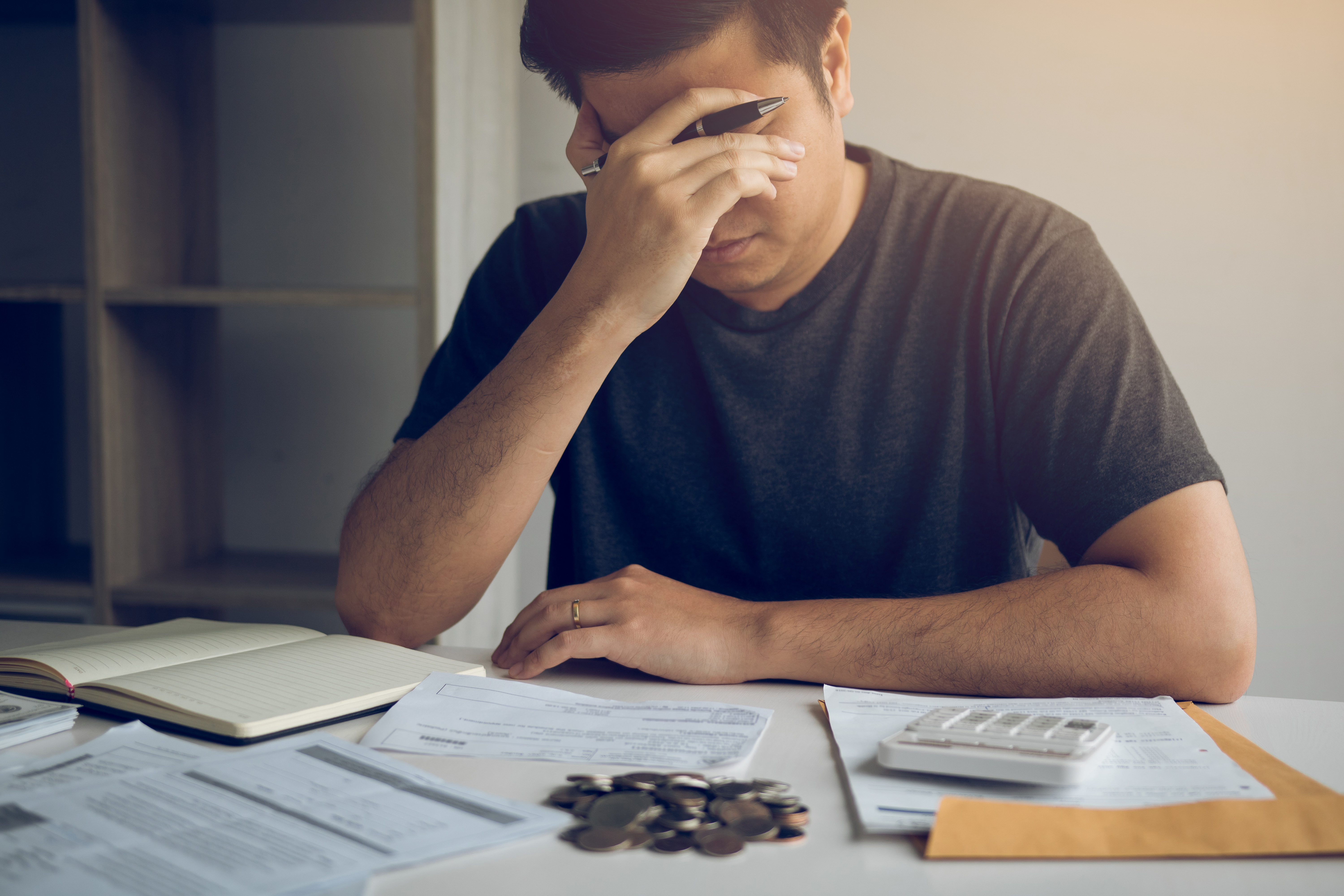 homem com expressão estressada fazendo contas e identificando erros financeiros em documentos.