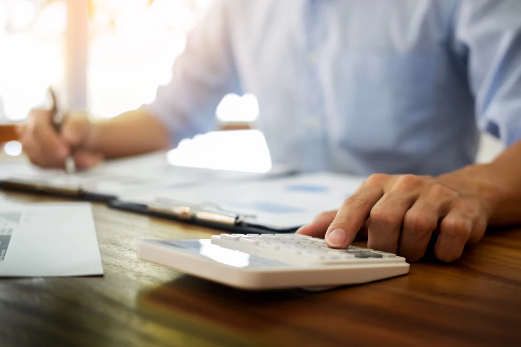 imposto de renda para mei: quem precisa declarar e como controlar suas finanças 1 empreendedor utilizando calculadora e caneta para calcular seu imposto de renda para mei.