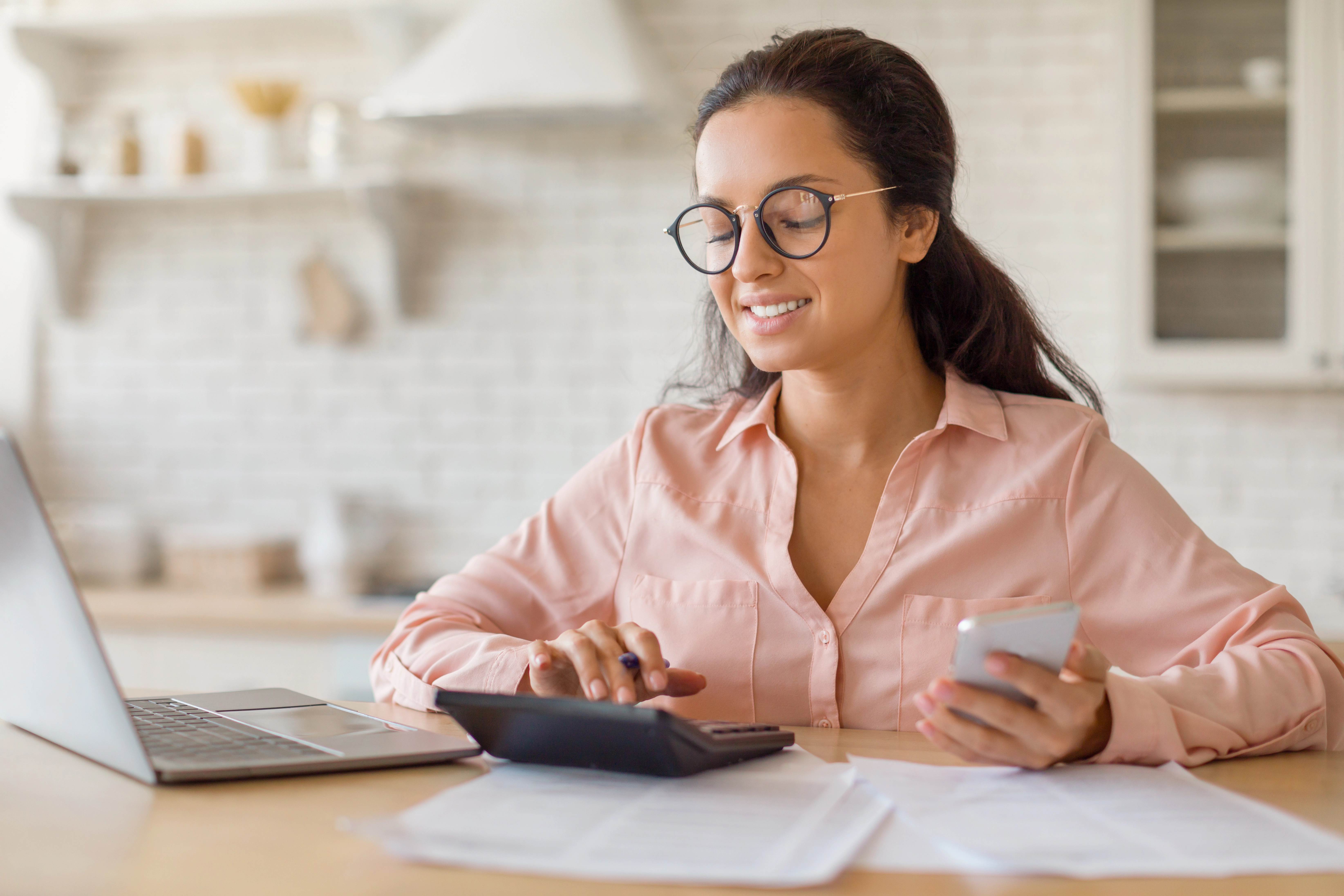 woman glasses kitchen table with laptop calculator phone